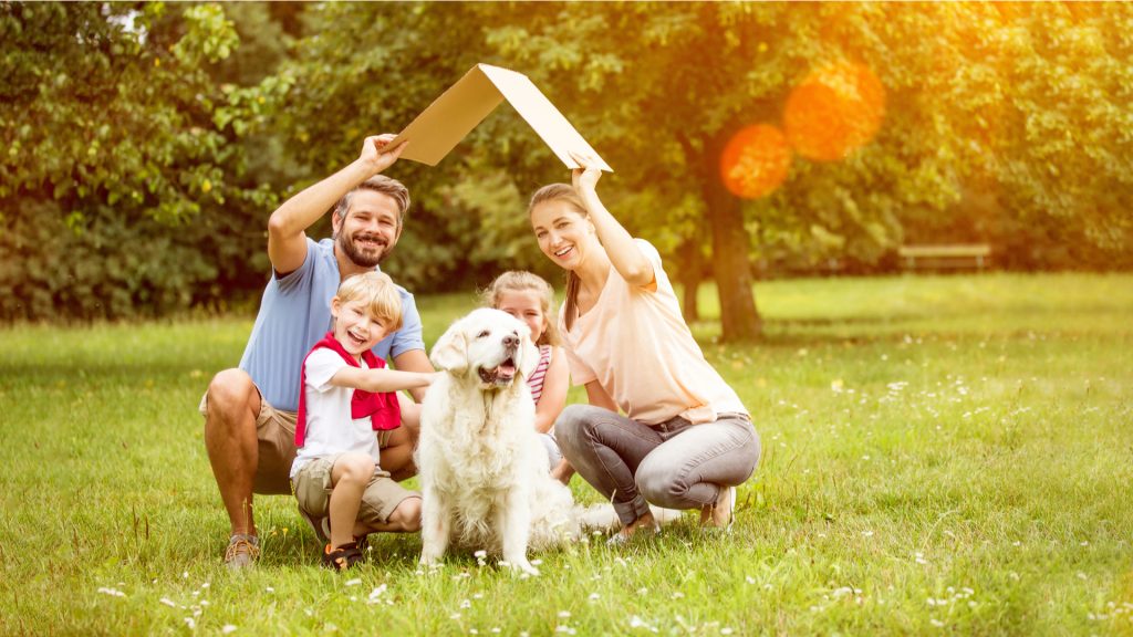 famille avec des enfants et un chien sous un toit en carton