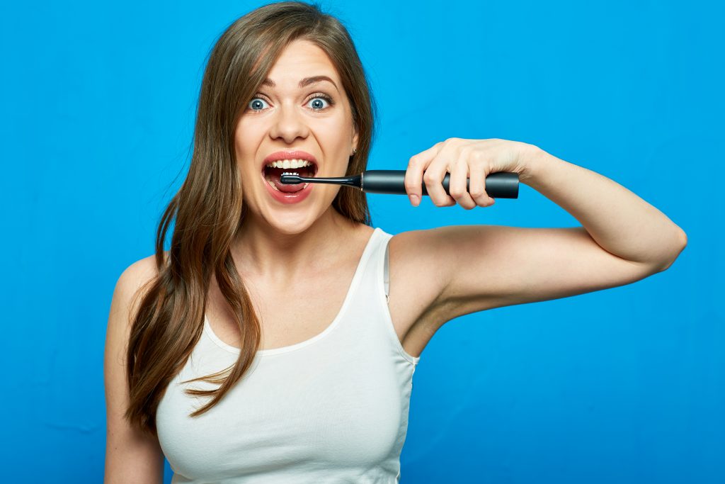 jeune femme se brosse les dent avec une brosse à dent électrique