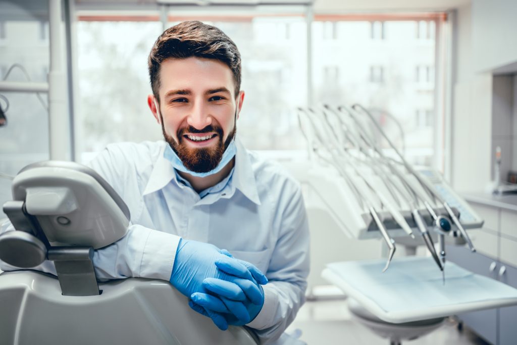 dentiste croisant ses gants de protection en souriant
