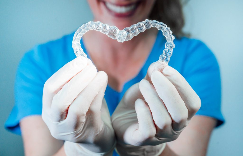 chirurgien dentiste faisant un cœur avec deux appareils invisalign