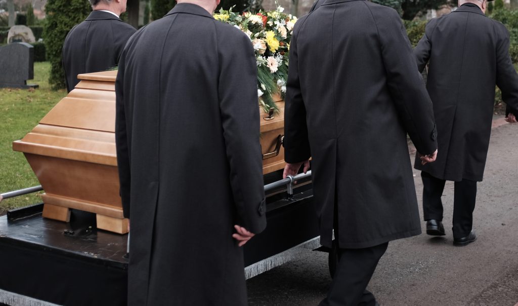 funérailles avec 4 hommes en noir et un cercueil