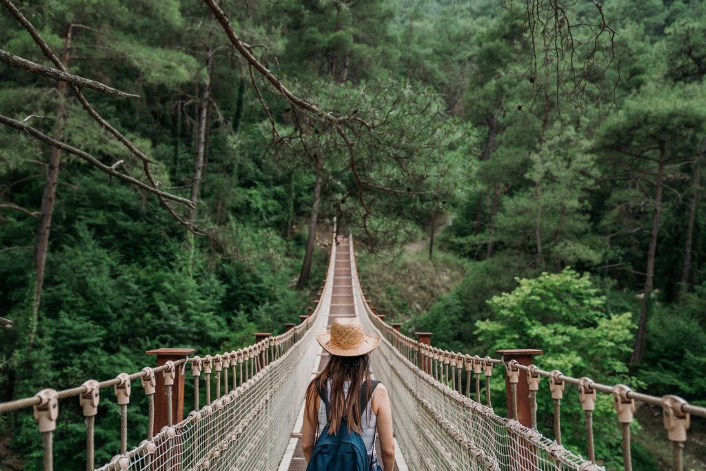 jeune femme sur un pont en corde au milieu de la forêt en voyage