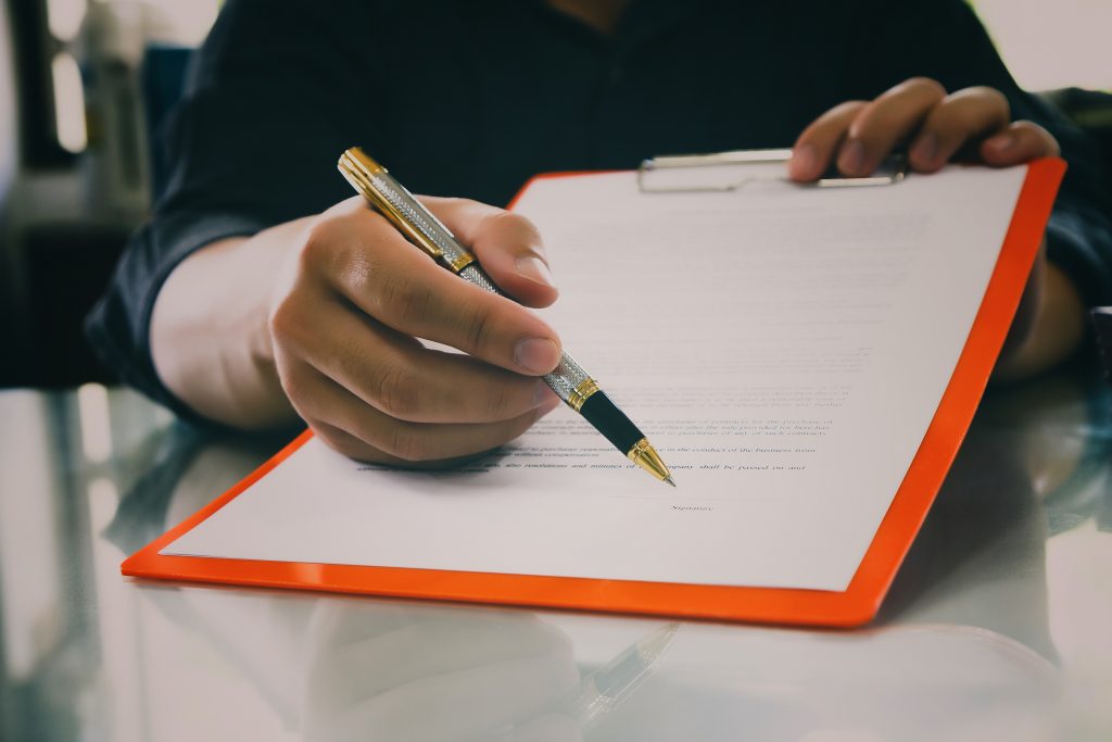 Homme avec stylo tendant une feuille à son client pour signer