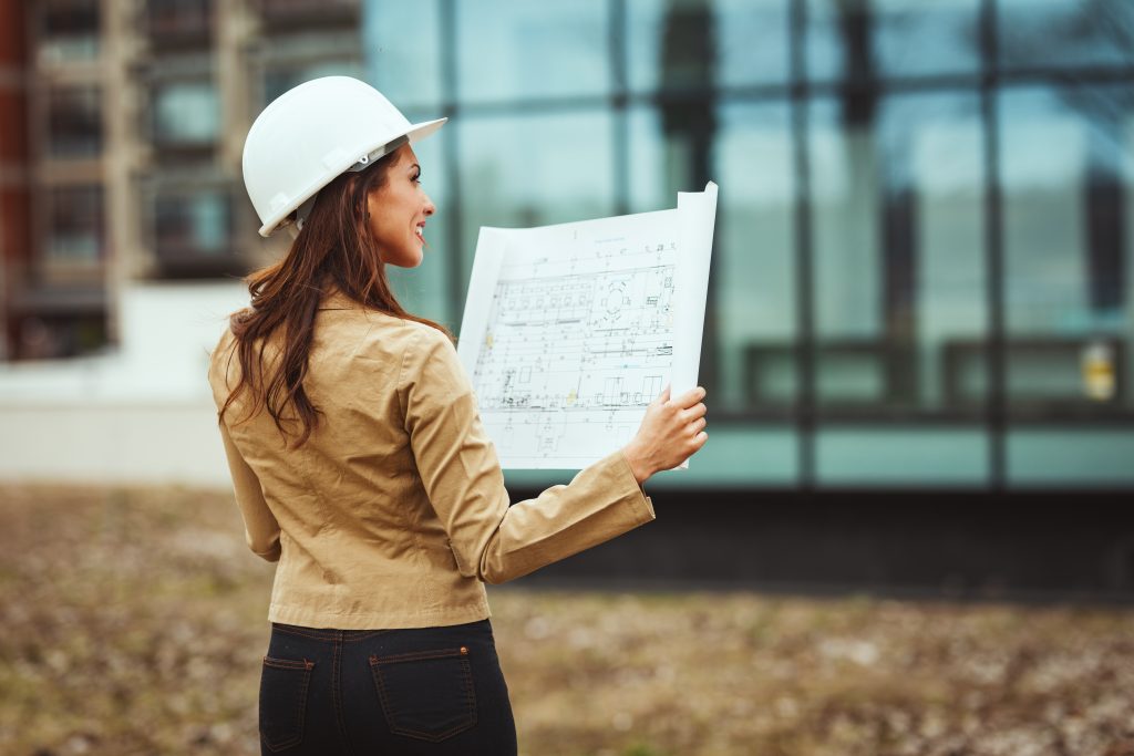 femme  avec casque blanc regardant des plans de bâtiment