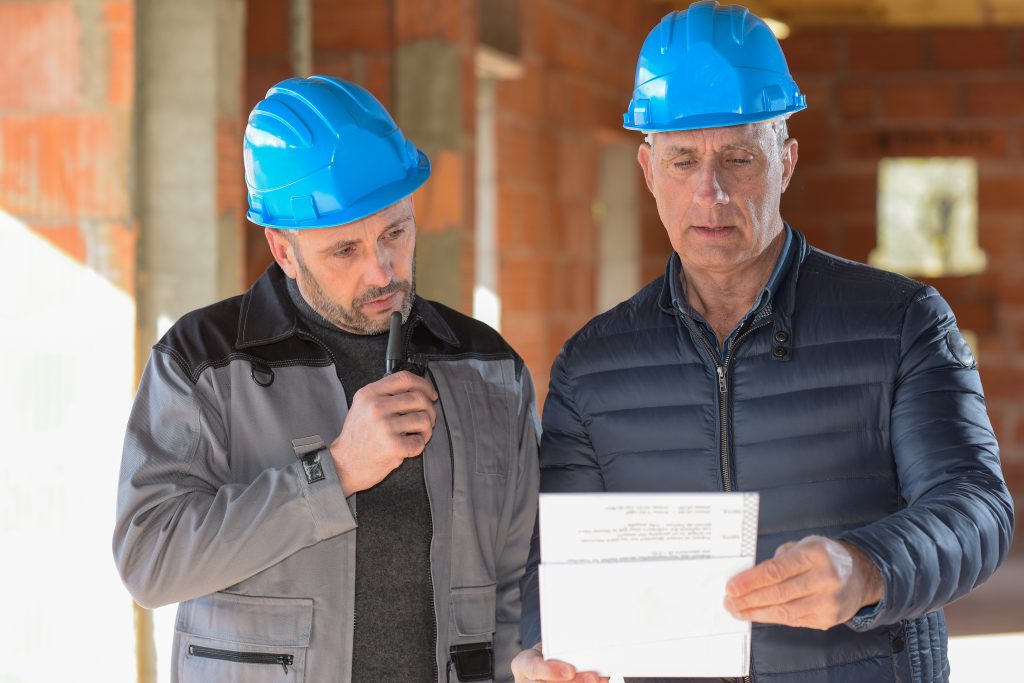 deux ouvriers avec des casques bleu regardant un papier