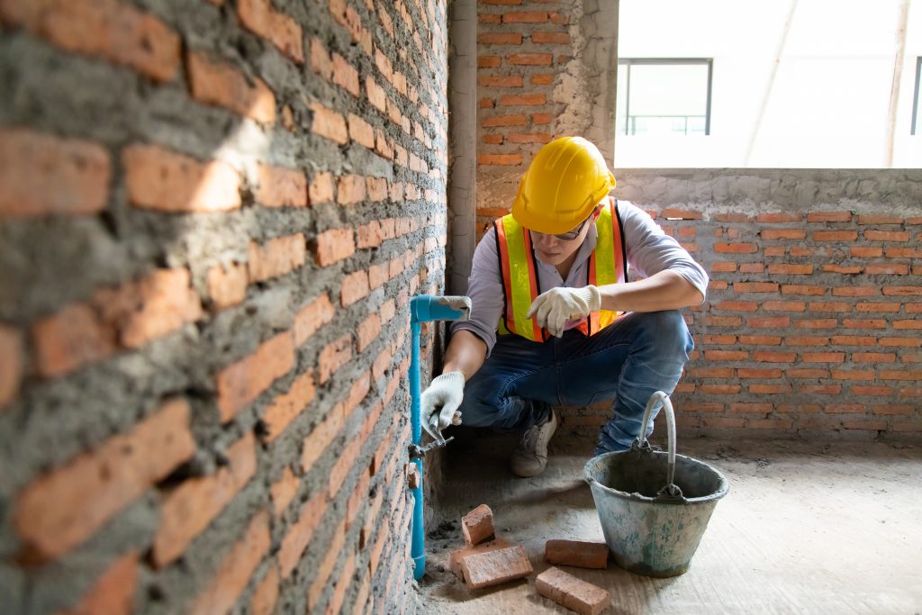 ouvrier à côté d'un mur en brique
