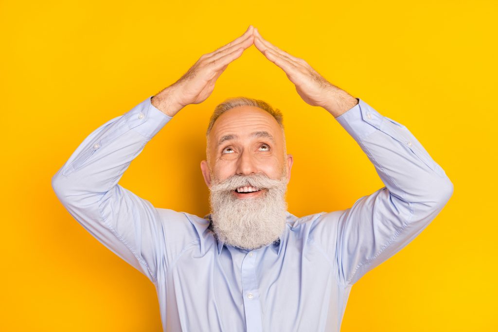 homme barbu sur fond jaune levant les mains